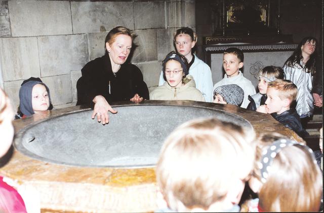 Annemarie Fenzl erklärt Kindern die Bedeutung des Taufbeckens.