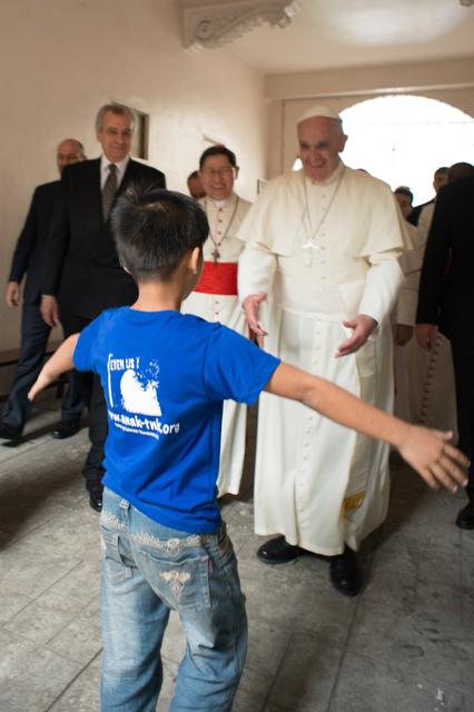 In Manila begegnet Papst Franziskus einem Straßenjungen. Beide kommen mit offenen Armen aufeinander zu.