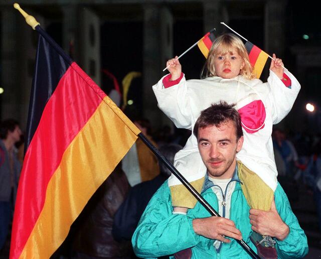 Vater und Tochter beim Fest in der Nacht zum 3. Oktober 1990 auf der Straße "Unter den Linden" in Berlin. Rund eine Million Menschen feierten in Berlin die wiedergewonnene staatliche Einheit, denn am 3. Oktober 1990 werden die Deutschen wieder in einem souveränen Staat vereint sein. | Foto: Andreas Altwein/dpa/picturedesk.com