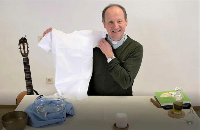 Per Video erklärt Pfarrer Christoph Goldschmidt die Bedeutung der Taufe, indem er ein weißes Taufkleid in Händen hält oder die Symbolik des Wassers und des Chrisamöls verständlich macht.