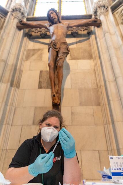 In Gottes Hand: Direkt unter dem mächtigen Kreuz in der barbarakapelle zieht die Ärztin der Malteser die vielleicht Lebensrettende Injektion auf. | Foto: Erzdiözese Wien/Stephan Schönlaub