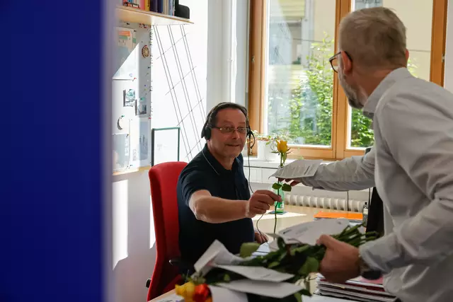 Bernhard Schwarzenegger überreicht einem AMS-Mitarbeiter eine Rose – als Zeichen der Wertschätzung am Tag der Arbeitslosen.  | Foto: Gerd Neuhold / Sonntagsblatt für Steiermark