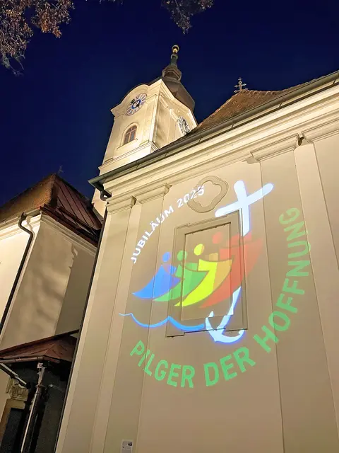 „Die Hoffnung lässt nicht zugrunde gehen“ – unter diesem Titel wurde das Heilige Jahr 2025 eröffnet. Das Logo mit Kreuz und farbenfrohen „HoffnungspilgerInnen“ projizierte die Pfarre Graz-Straßgang auf ihre Kirche. | Foto: Karlheinz Weber