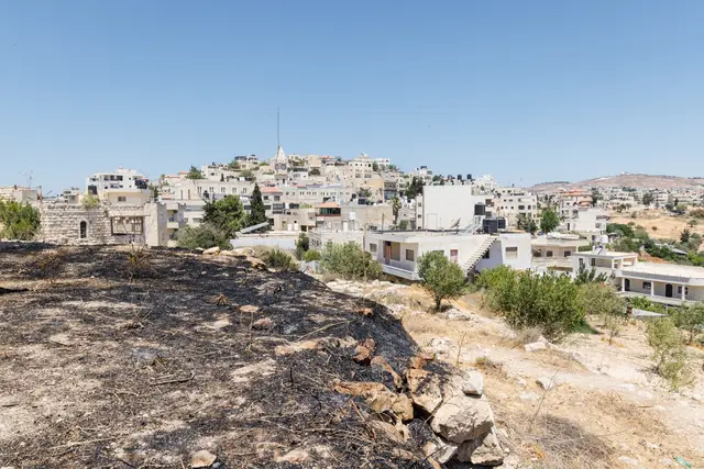 Blick auf Taybeh. Gemäß der Bibel soll sich Jesus vor seiner Passion dorthin zurückgezogen haben. Heute ist das Dorf der einzige fast komplett christliche Ort im Heiligen Land. Das Foto vom 14. Juli 2025 zeigt im Vordergrund Spuren eines Angriffs durch radikale SiedlerInnen – Taybeh ist umgeben von israelischen Siedlungen und Militärbasen. | Foto: Andrea Krogmann/KNA