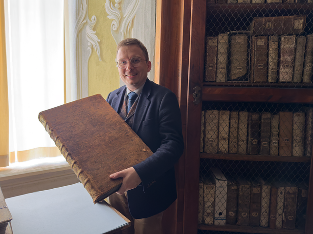 Markus Bürscher mit seinem Lieblingsbuch: einer großen mittelalterlichen Bibel-Handschrift. | Foto: Patricia Harant-Schagerl