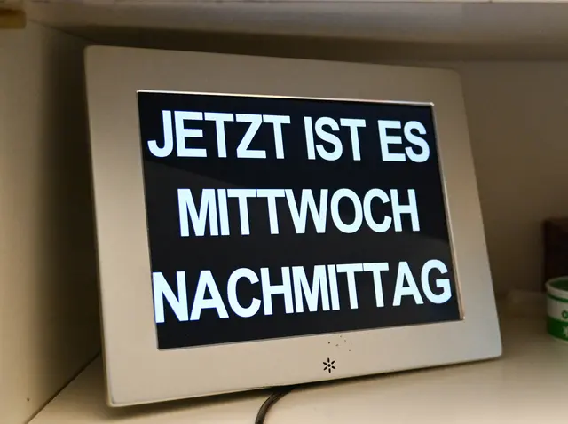 Hilfe im Alltag. Fotos auf Türen; farbige Merkzettel, sprechende Zeitplaner: Alltagshilfen erleichtern Menschen mit Demenz die Organisation ihres Tages und fördern die Selbstständigkeit. Im Bild eine Kalenderuhr mit ausgeschriebenen Wochentagen zur Erleichterung der zeitlichen Orientierung. 