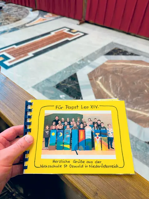 Der St. Oswalder Kaplan Thomas Schmid überreicht dem Papst ein Buch, gestaltet von Kindern aus seiner Pfarre. | Foto: zVg/Vatican Media